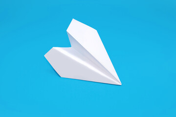 White paper plane on a blue background in the center. Paper origami in the form of a small...