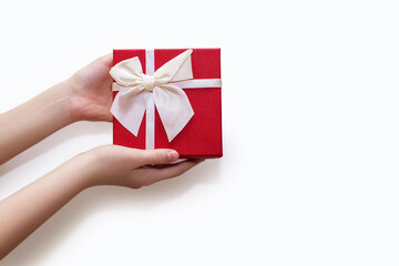 Red gift box in human hands on a white background. Beautiful gift box decorated with ribbon and bow. The concept of giving gifts for birthday or traditional holidays. Free space for text