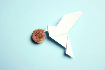 Paper origami dove of peace with bitcoin on a blue background.