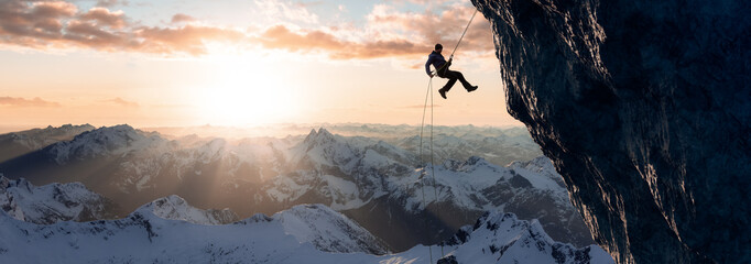 Adult adventurous man rappelling down a rocky cliff. Extreme adventure composite. 3d rendering mountain artwork. Aerial background landscape from British Columbia, Canada. Cloudy Sunset Sky