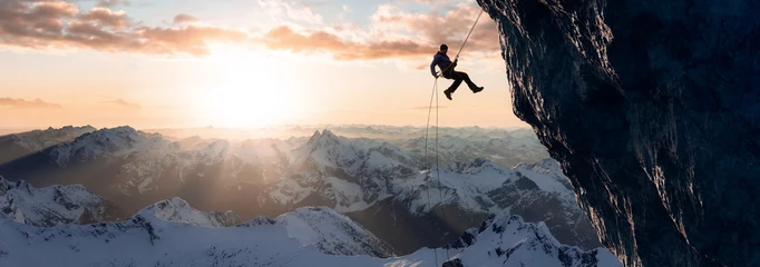 Foto op Canvas Adult adventurous man rappelling down a rocky cliff. Extreme adventure composite. 3d rendering mountain artwork. Aerial background landscape from British Columbia, Canada. Cloudy Sunset Sky © edb3_16