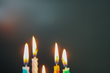 Burning multicolored candles in the dark background with copy space.
