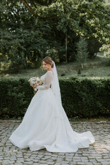 Fototapeta na wymiar Gorgeous stylish bride in vintage white dress walking in the park
