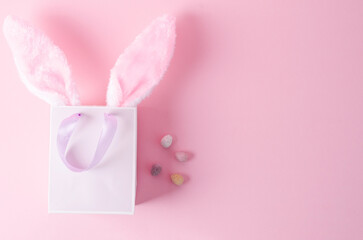 The concept of shopping for Easter. Paper bag on a pink background with bunny ears on a pink background, flat layout