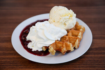 Eine heiße Waffel mit Kirschen, Eis und Sahne.
