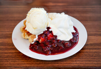 Eine heiße Waffel mit Kirschen, Eis und Sahne.
