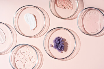 Cosmetic products, scrub, face serum and gel in many petri dishes on a pastel beige background....