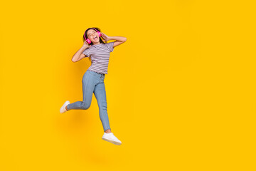 Fototapeta na wymiar Full length photo of young girl excited enjoy music earphones melody walk isolated over yellow color background