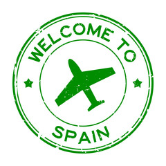 Grunge green welcome to Spain word with airplane icon round rubber seal stamp on white background