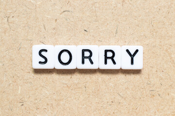 White tile alphabet letter with word sorry on wood background