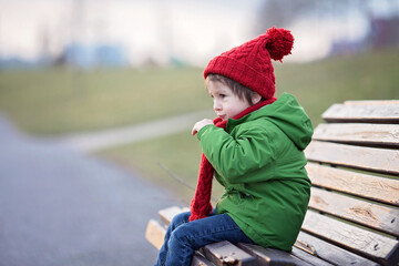 Little boy, sneezing and blowing his nose outdoor on a sunny winter day