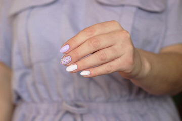 purple glamor manicure long nails with crystals one hand on a lilac background