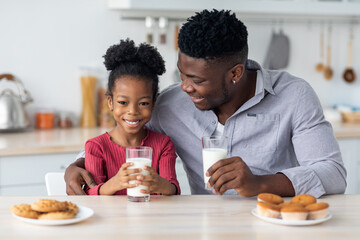 Cheerful african american father and daughter enjoying fresh milk