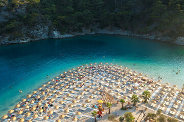 aerial view to beach with sun umbrellas in bay with emerald water in city Oludeniz in Turkey