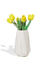 Subject shot of a graceful bouquet of tender yellow tulips in a white ceramic vase. The bouquet of flowers for interior decorating is isolated on the white background. 