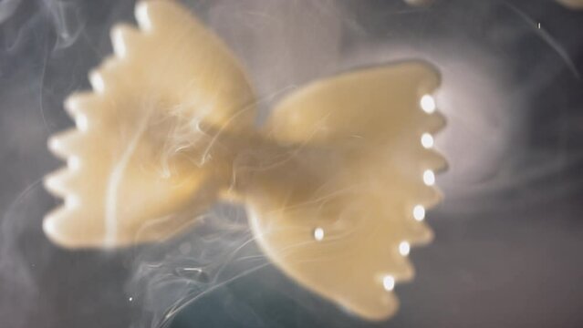 Pasta Farfalle is flying up on a kitchen bokeh background