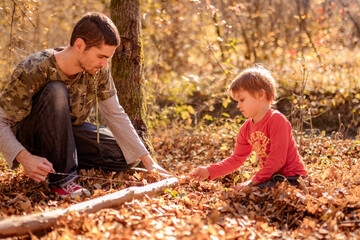 father and son saw a log with a wire saw in camp autumn, spending time together