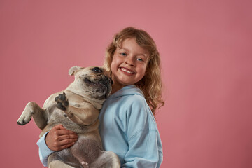 Happy caucasian little girl holding French bulldog