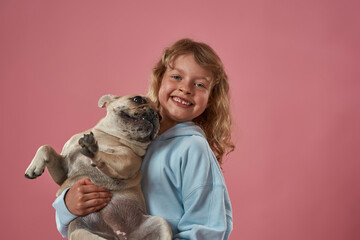 Obraz premium Happy caucasian little girl holding French bulldog