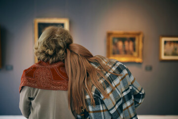 A grandmother and her grandchild enjoying the painting exhibition at gallery.