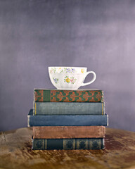 Vertical shot of a teacup on a stack of vintage books