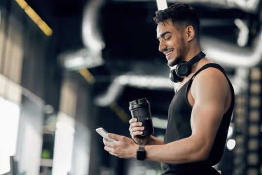 Fitness App. Smiling Arab Sporty Man Using Smartphone While Standing In Gym - Powered by Adobe