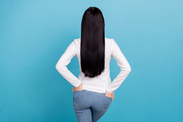 Back photo of young brunette lady wear white outfit jeans isolated on blue color background