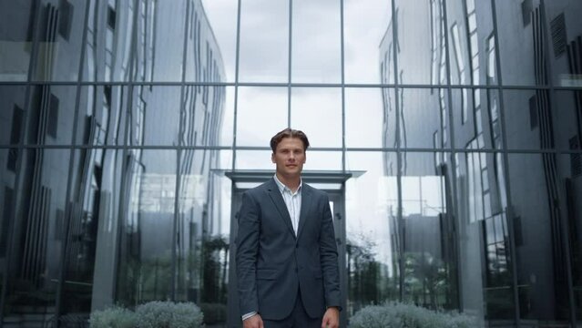 Portrait businessman posing at modern glass office building alone. 