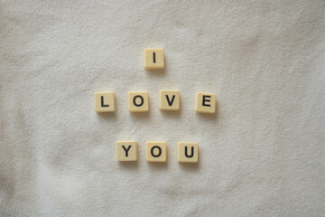 I love you written with scrabble / banagram block letters on soft white fleece background - Powered by Adobe