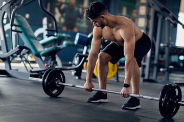 Fototapeta na wymiar Shirtless Arab Man Making Deadlift Workout With Barbell At Modern Gym