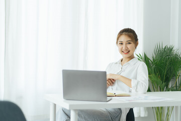 Charming asian businesswoman sitting working on laptop in office.
