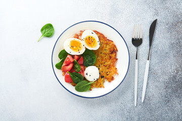 Breakfast. Potatoes latkes with sour cream, spinach salad, tomatoes and boiled eggs on light background. Delicious food for breakfast. Top view. - obrazy, fototapety, plakaty