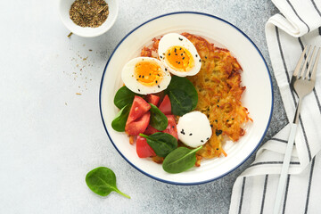 Breakfast. Potatoes latkes with sour cream, spinach salad, tomatoes and boiled eggs on light background. Delicious food for breakfast. Top view.
