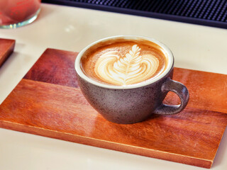Latte art coffee on wooden plate.