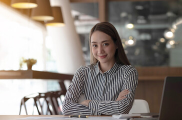 Charming Asian woman working at the office using a laptop Looking at the camera.