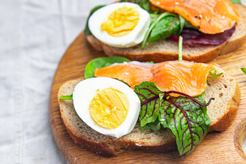 sandwich salmon smorrebrod egg, green salad mix, cereal bread toast seafood open fresh portion meal food snack on the table copy space food background 