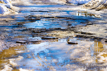 A broken sidewalk. Puddles on the sidewalk of melted snow. The concept of poor-quality paving slabs. a sidewalk washed away by water. destroyed sidewalk. Close-up.