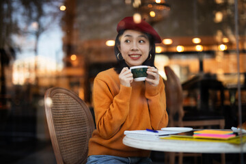 Beautiful Chinese woman drinking coffee in cafe. Young smiling woman enjoy in restaurant