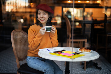 Beautiful Chinese woman drinking coffee in cafe. Young smiling woman enjoy in restaurant