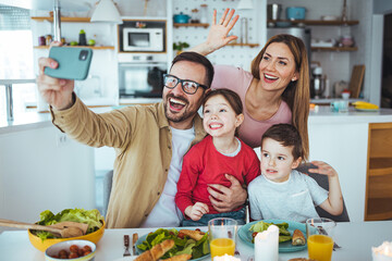 Smiling father holding cellphone, making selfie shot, recording video with happy wife and little kids siblings. Excited parents looking at mobile screen with kids, feeling excited.