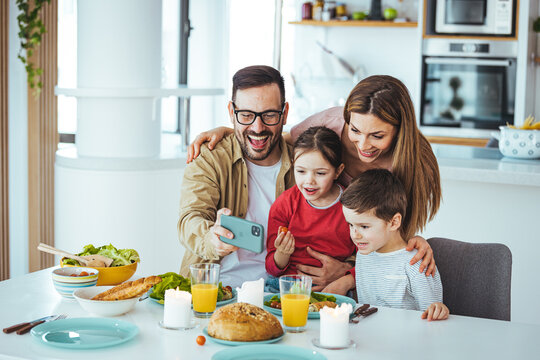 Smiling father holding cellphone, making selfie shot, recording video with happy wife and little kids siblings. Excited parents looking at mobile screen with kids, feeling excited.