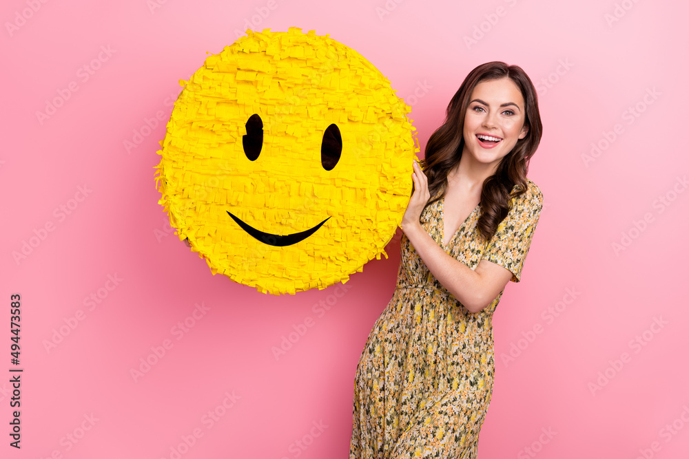 Poster Photo of sweet young brunette lady hold pinata wear floral dress isolated on pink color background