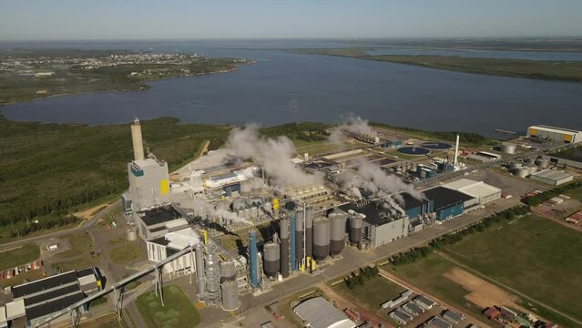 Aerial panoramic view over smoking chimneys of paper mill factory at Fray Bentos along Uruguay river