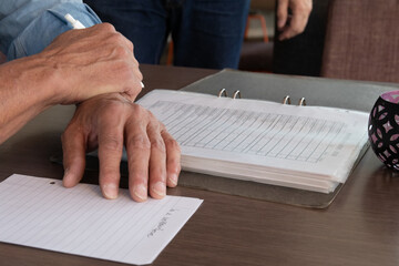 Closeup of the man's hands on the table with journal and paper.