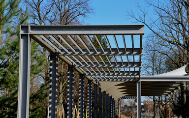 white canvas stretched, shading from the sun and rain over the terrace of the restaurant, on the playground in the kindergarten, on the platform of the promenade. pergola with metallic gray beams  - obrazy, fototapety, plakaty