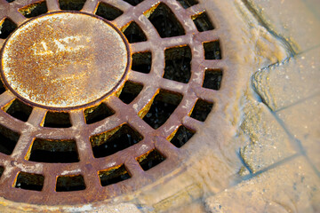 draining water into the manhole through the grate. sewer grate. round sewer cover. Close-up.