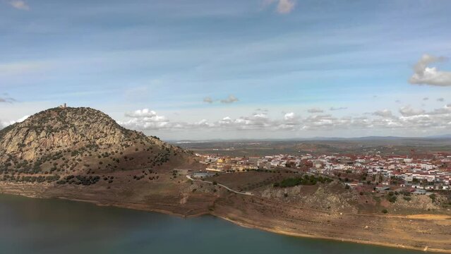 Aerial images of the Extremaduran town of Alange from the reservoir. With magnificent views of the Castillo de la Culebra. Sideward flight. Magnificent sky.