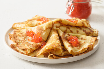 Thin pancakes with red caviar on white background. Russian traditional breakfast for Shrovetide.