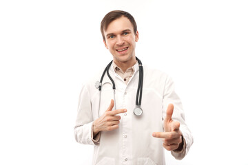 Fototapeta premium Portrait of friendly positive young male doctor in white medical coat chooses you, points finger at camera isolated on white background.