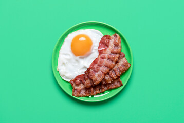 Fried egg and bacon on a green background, above view